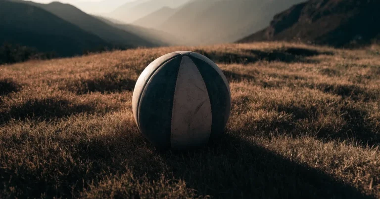 Ein Fussball auf einem staubigen Rasenstück in der Abendsonne, im Hintergrund eine hohe Bergkette